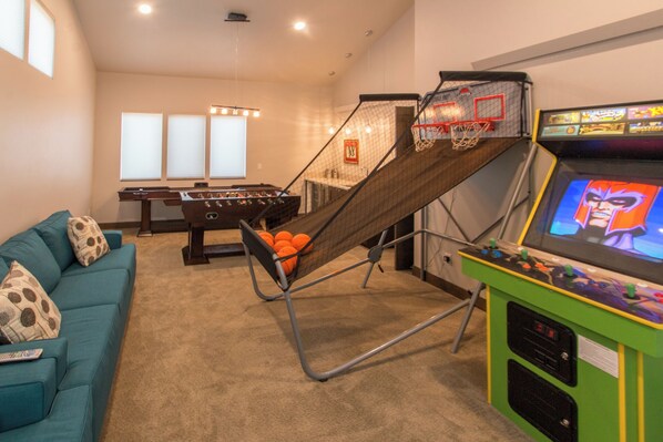 Une salle de loisirs équipée d’un baby-foot, d’une table de billard, d’un canapé et d’une console de jeux vidéo.