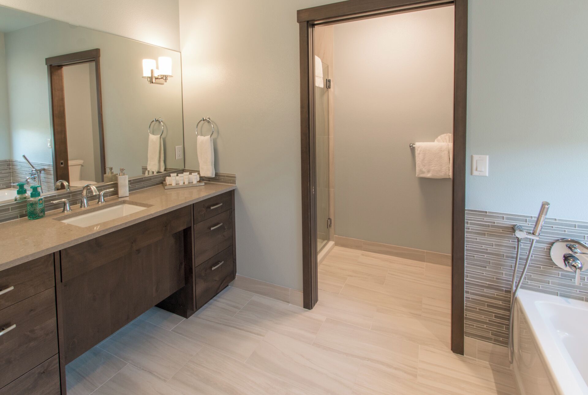 Un bagno moderno con doppio lavabo, cabina doccia in vetro e doccia a filo pavimento.