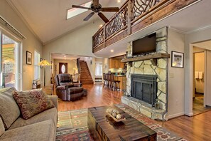 A spacious living area with a fireplace, a high ceiling fan, and a staircase leading to another level. - Mountain Cabin with Fire Pit, Hot Tub, Pool, Tennis & Golf in Sky Valley (Sky Valley)