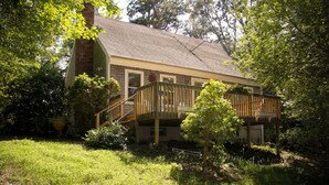 A house with a wooden deck, a brick chimney, and a garden.