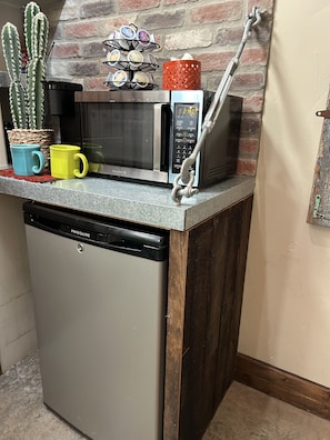 Cocina compacta con lavavajillas integrado, microondas y cafetera sobre la encimera.