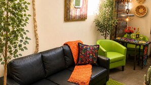 Un salon avec un canapé en cuir noir, des fauteuils verts, une table basse et un panneau mural sur lequel on peut lire : « Détendez-vous ».