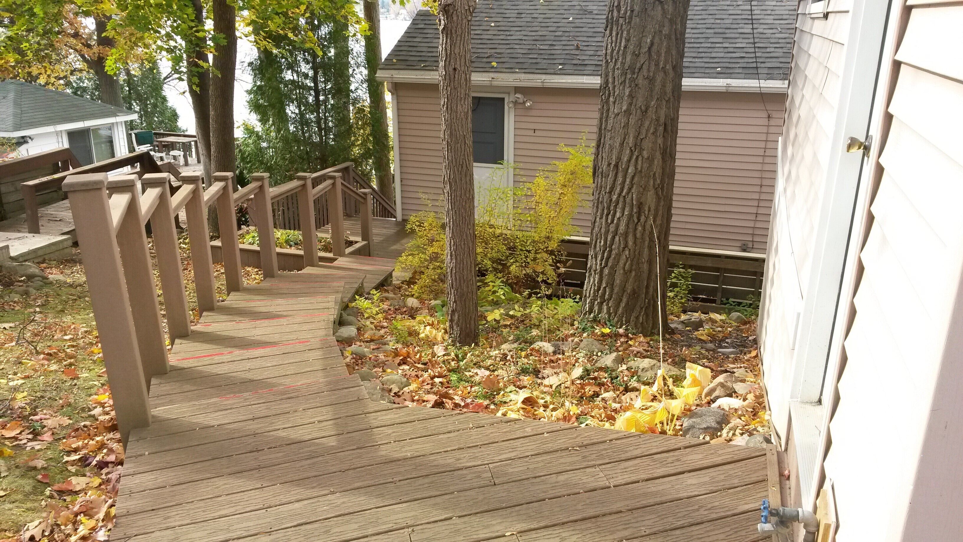 A wooden deck leading to a house with a covered porch area.