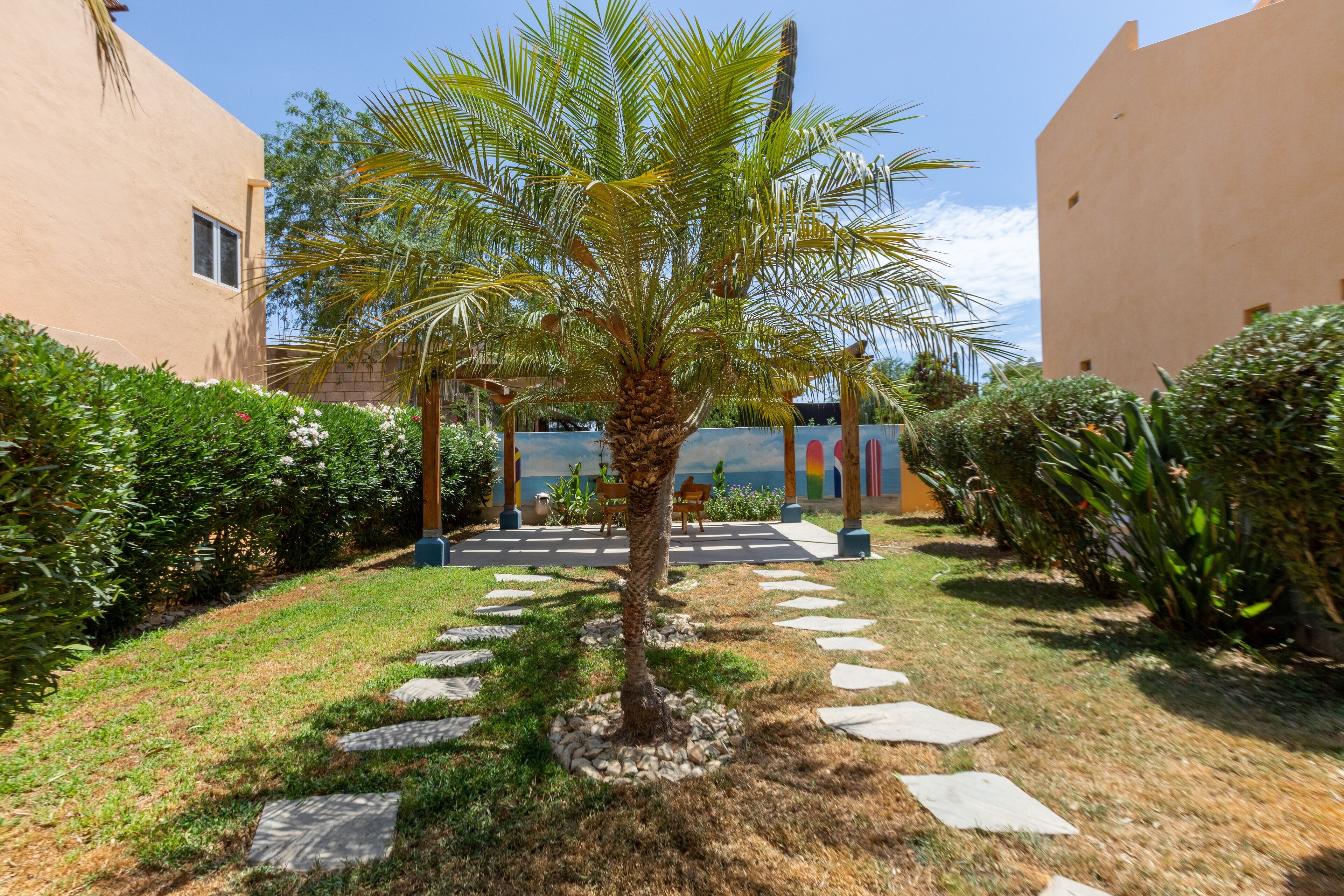 A courtyard with a palm tree, stone pathway, and a seating area with a table and chairs.