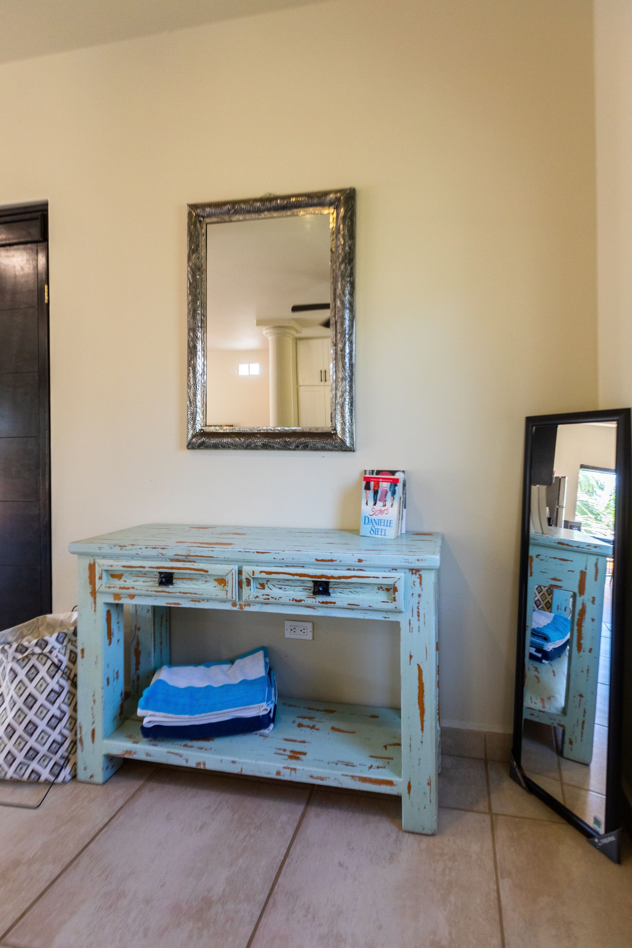 A rustic, light blue wooden desk with a shelf, a mirror, and a Daniele's brand box on it.