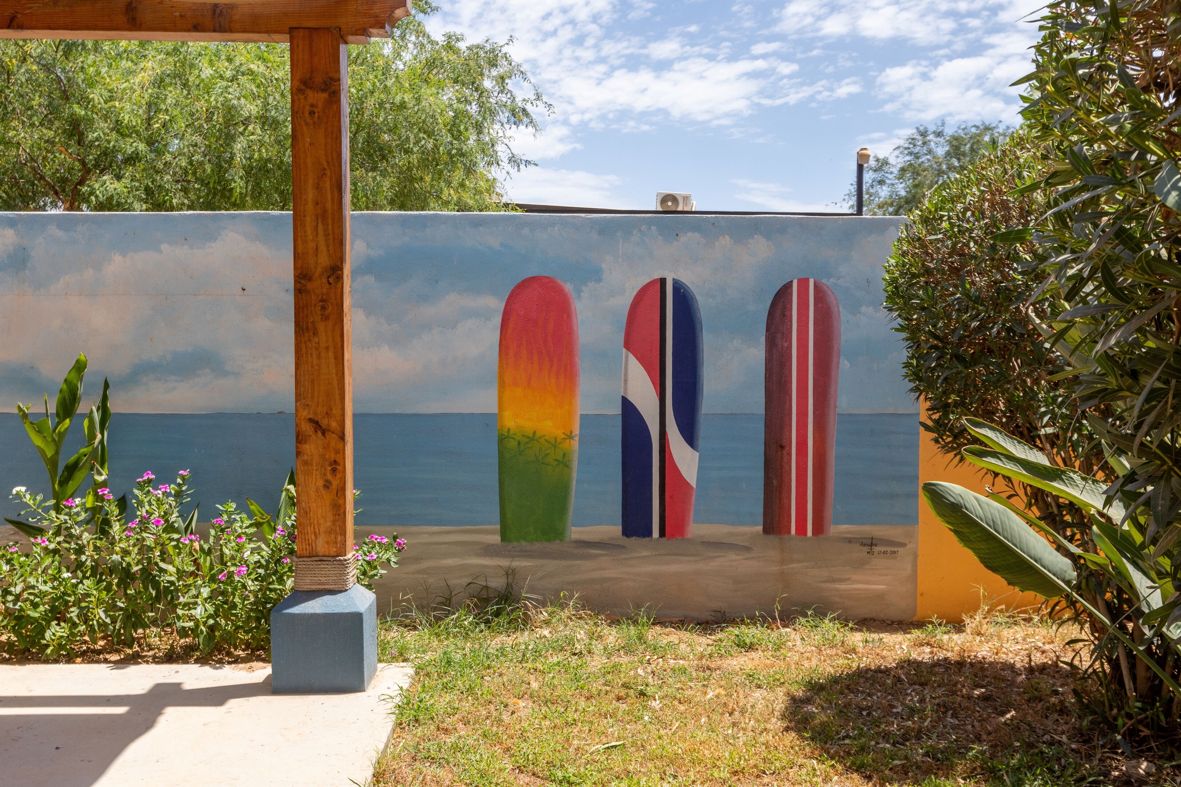 A mural of surfboards on a wall with a beach and ocean in the background.