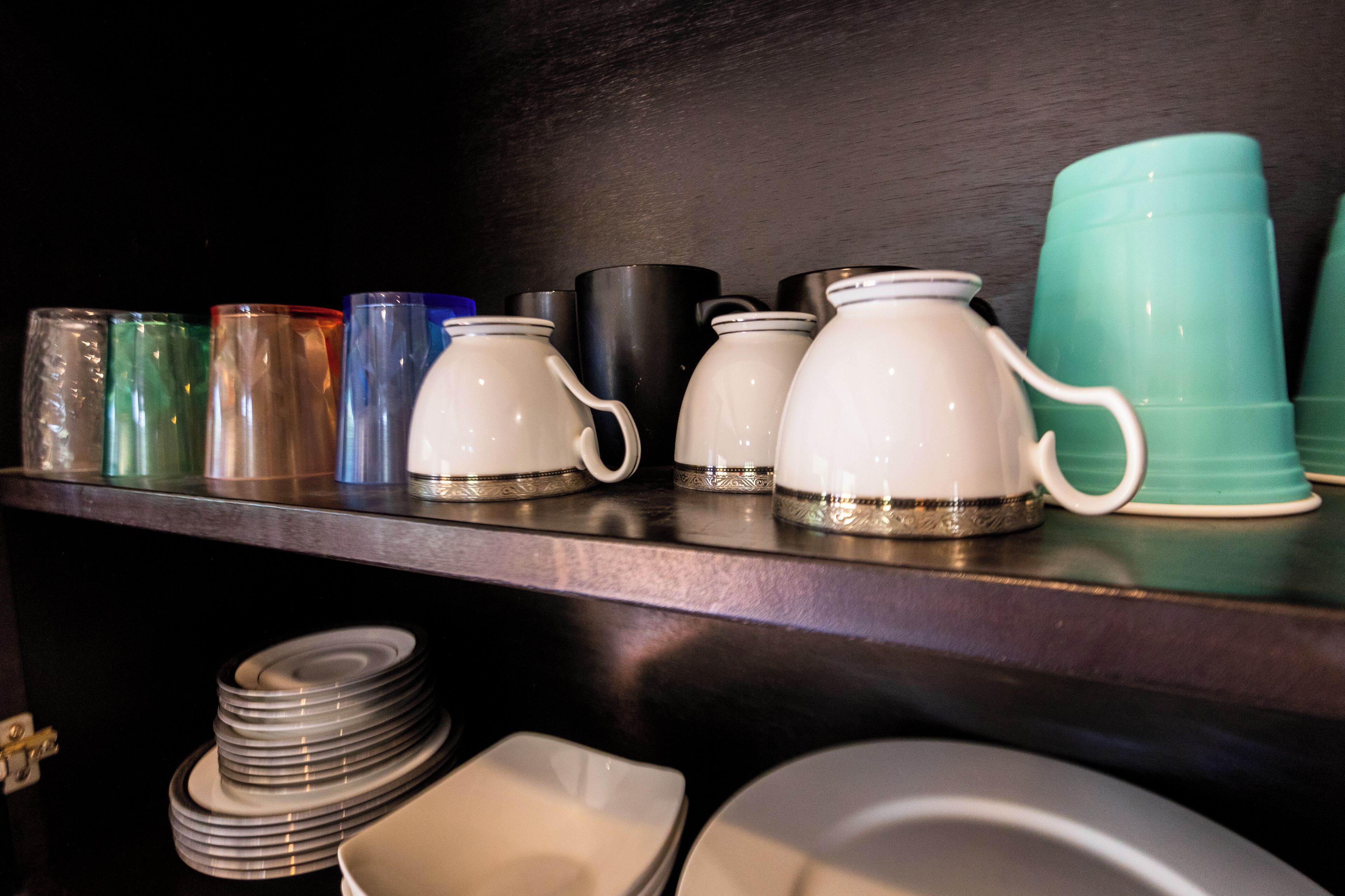 A shelf with various kitchenware including plates, bowls, and cups.