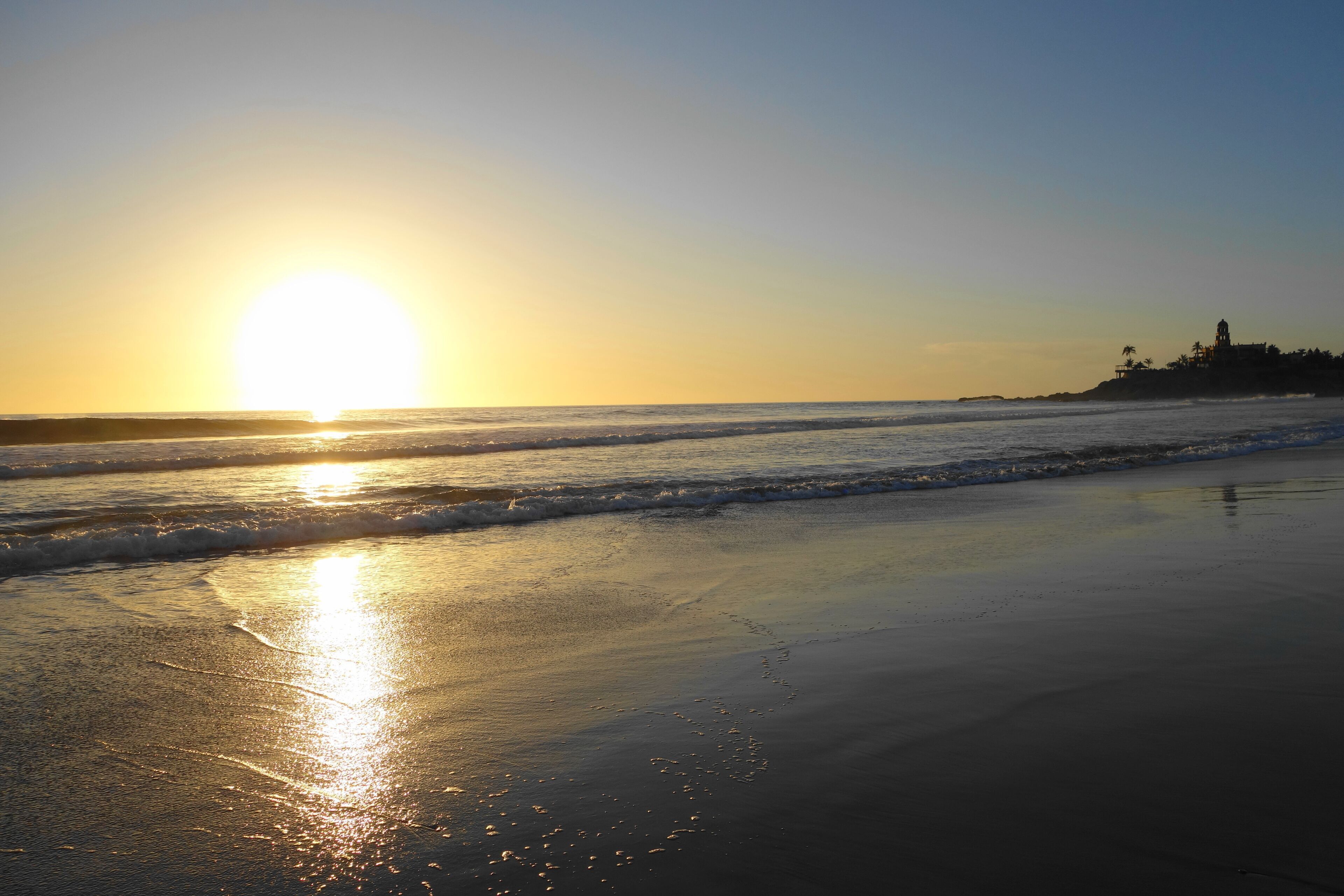 A beach with the sun setting over the ocean, creating a calm and serene atmosphere.