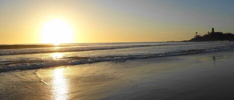 A beach with the sun setting over the ocean, creating a calm and serene atmosphere.