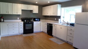 A modern kitchen with white cabinets, a black stove, a dishwasher, and a refrigerator.