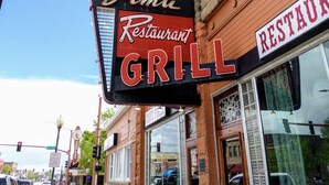 A restaurant sign for 'Grima Restaurant Grill' on a building with a brick facade and large windows.