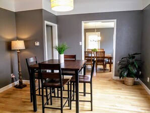 A dining area with a wooden table and chairs, a potted plant, and a lamp. - Historic 3 Bedroom Home in Downtown Cody!  (Cody)