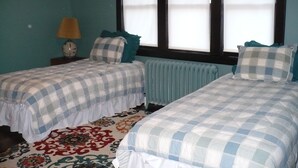 A room with two beds, a radiator, a lamp, and a patterned carpet.