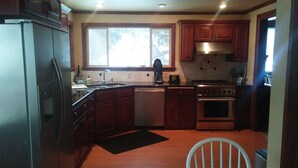 A kitchen with wooden cabinets, a dishwasher, a stove, and a sink.