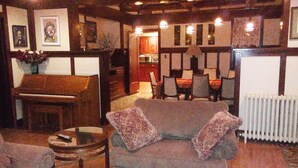 A cozy living room with a piano, a sofa, and a dining table with chairs.