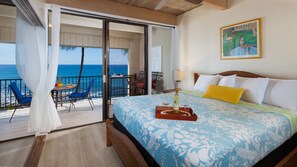 A hotel room with a bed, a table with a drink, and a view of the ocean.