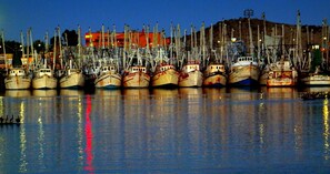Un port de plaisance où de nombreux bateaux sont amarrés dans une eau calme, et où se reflètent les bateaux et les bâtiments environnants.