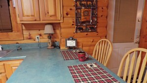 A kitchen with wooden cabinets, a blue countertop, a plaid placemat, a red mug, and a wall-mounted decoration. - Breathtaking views from decks! Private acres next door to Dollywood! Beautiful! (Pigeon Forge)