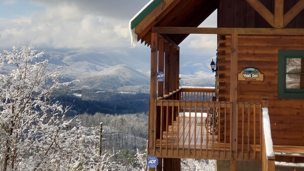 A wooden cabin with a balcony, surrounded by snow-covered trees and mountains in the background. - Breathtaking views from decks! Private acres next door to Dollywood! Beautiful! (Pigeon Forge)