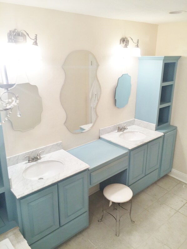 A bathroom with two sinks, a large mirror, and a blue cabinet.