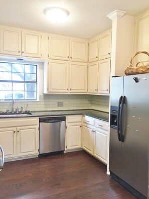 A kitchen with white cabinets, a stainless steel refrigerator, and a dishwasher.