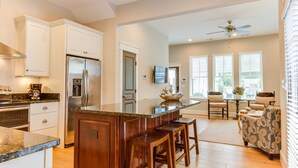 A modern kitchen with a central island, built-in appliances, and a dining area with a ceiling fan. - 4BR townhome near the beach with parking, WiFi, and pet-friendly stays. (Virginia Beach)