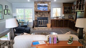A cozy living room with a fireplace, a sofa, a coffee table, and a bookshelf. - Newly Renovated Lakeside Cottage, Beautiful Lake Views With Adjacent Boat Ramp. (Dover)