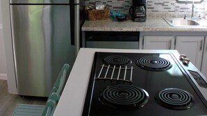 A kitchen with a stainless steel refrigerator, a black stove, and a tiled backsplash. - Newly Renovated Lakeside Cottage, Beautiful Lake Views With Adjacent Boat Ramp. (Dover)