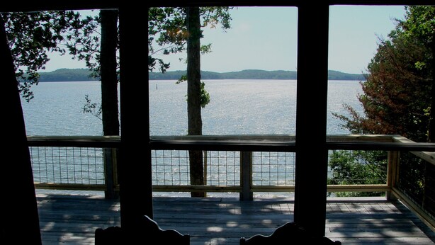 A view from a wooden deck overlooking a calm lake with distant hills. - Newly Renovated Lakeside Cottage, Beautiful Lake Views With Adjacent Boat Ramp. (Dover)