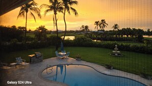 A swimming pool with a view of palm trees and a sunset. - SANIBEL SUN CASTLE  Splendid home, heated pool, great location, bike to beach. (Sanibel)