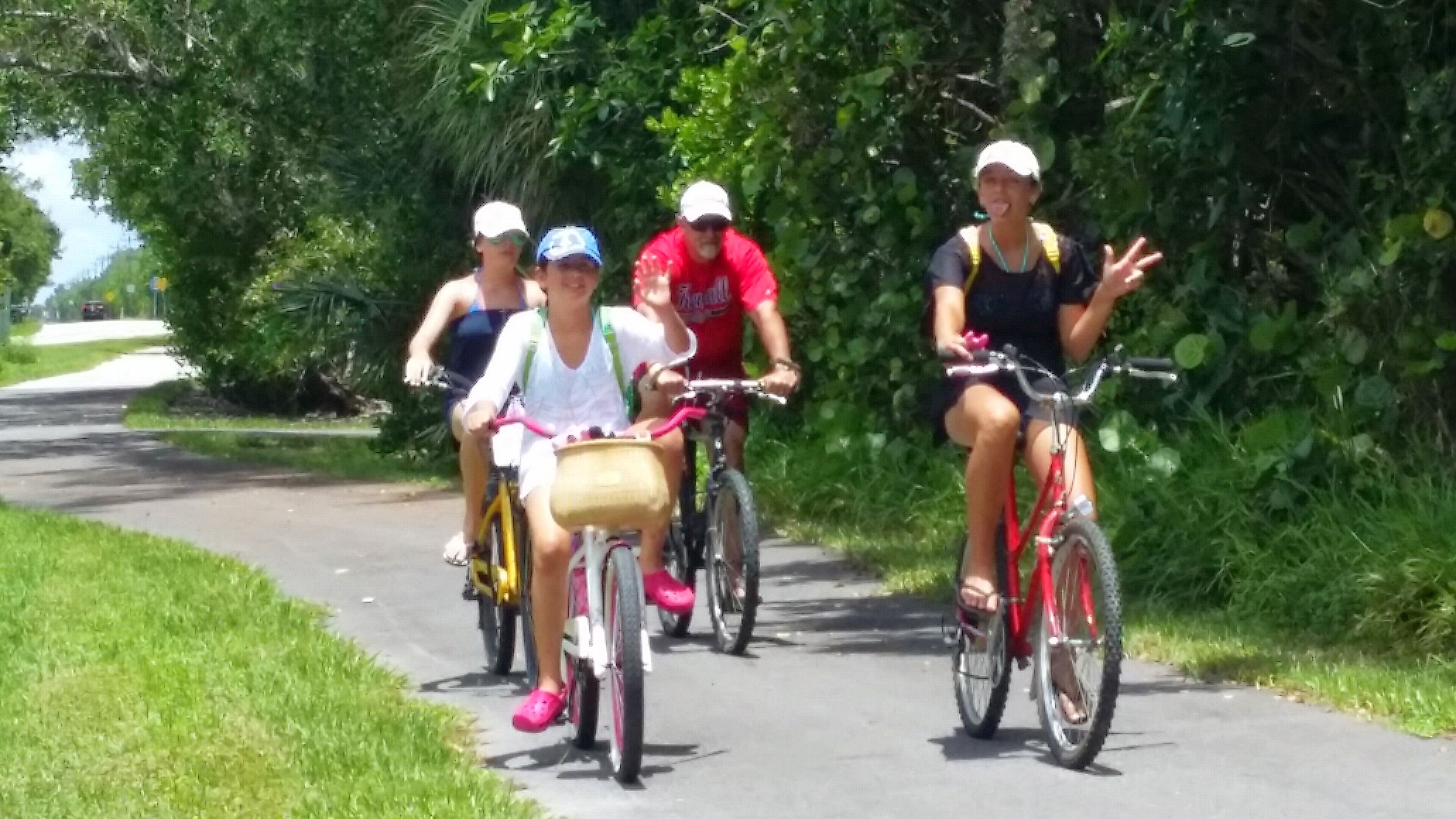 Un groupe de personnes fait du vélo sur une piste asphaltée, entourée de verdure.