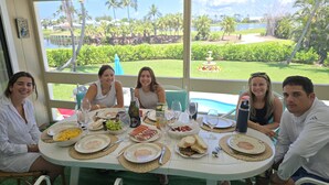 A group of people seated around a table with food and drinks, overlooking a pool and greenery. - SANIBEL SUN CASTLE  Splendid home, heated pool, great location, bike to beach. (Sanibel)