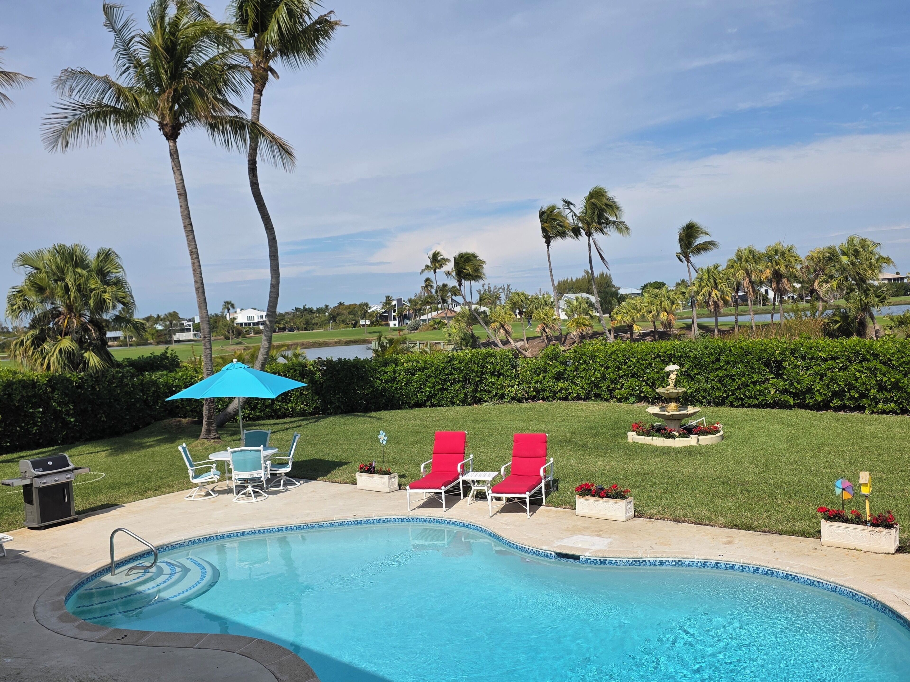 A pool area with a view of a golf course and a lake.
