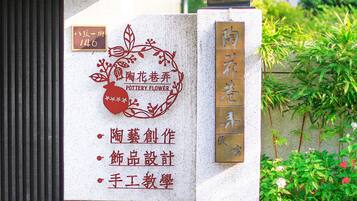 A signboard with a logo and text indicating a pottery flower shop, including services like pottery creation, product design, and handwork education.