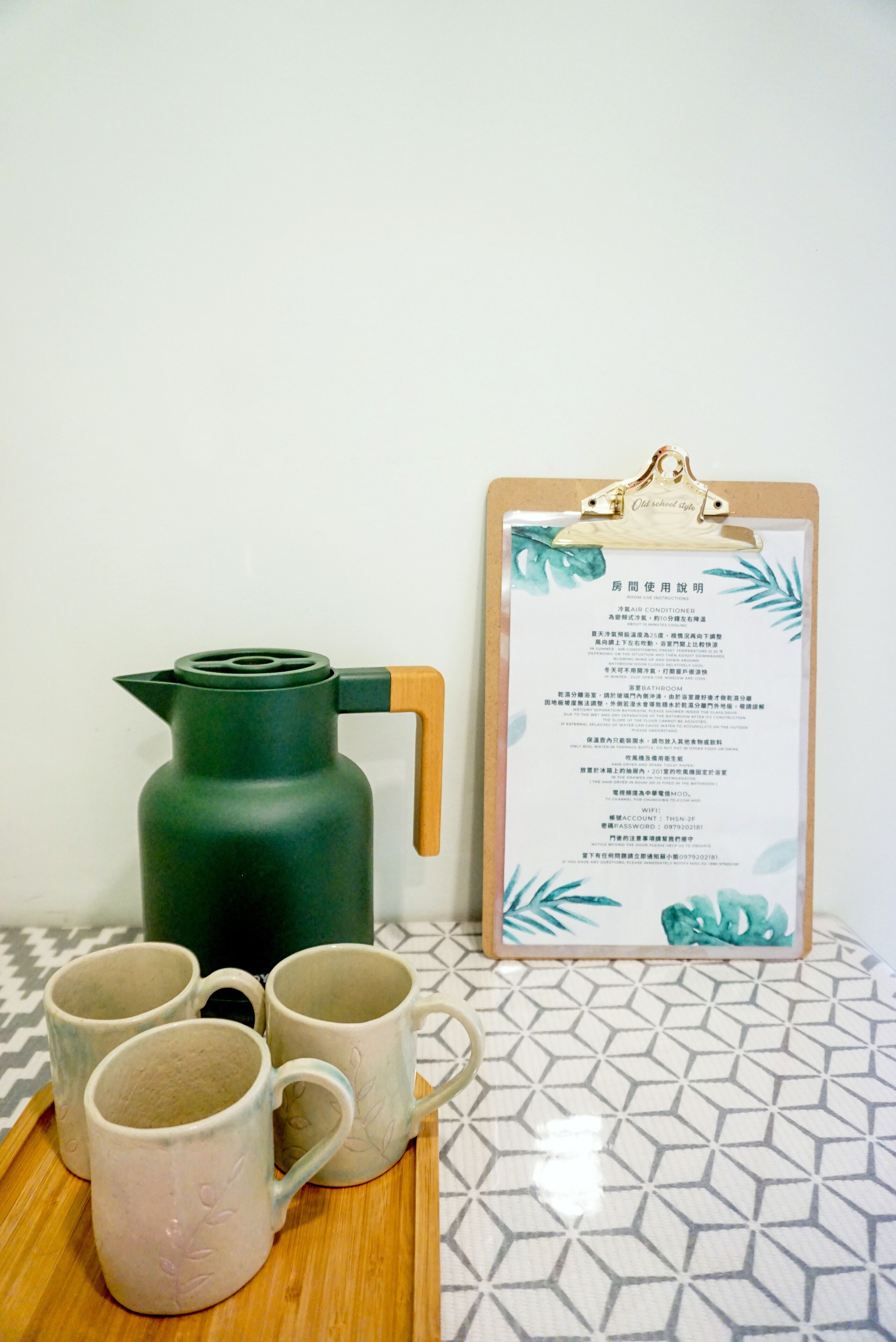 A room with a wooden table, a green kettle, and a clipboard with a menu.