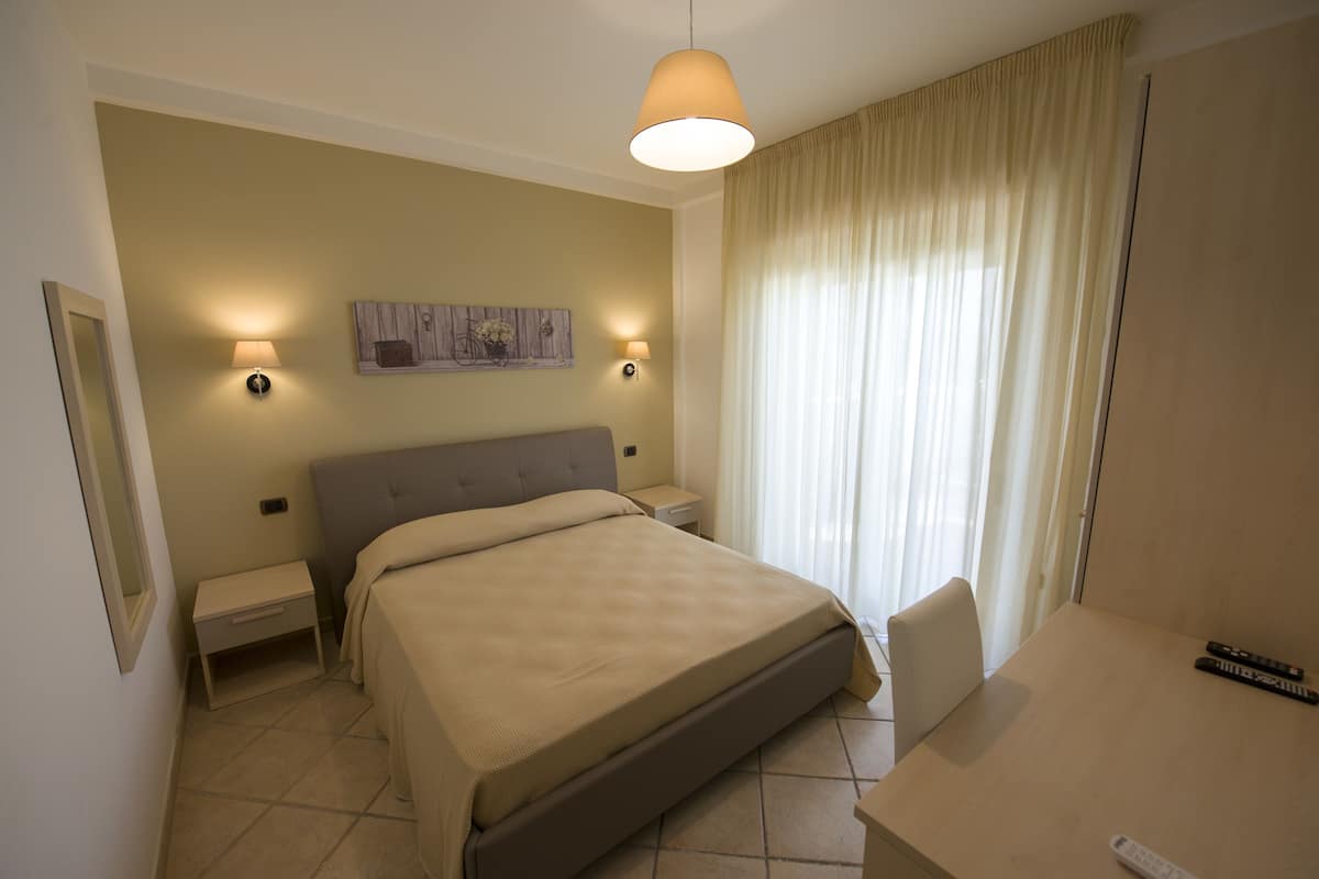 Una habitación de hotel con cama, mesitas de noche, escritorio y lámpara.