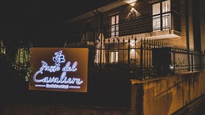 Un bâtiment sur lequel est apposée une enseigne au néon indiquant : « Passe del Cavalier, chambre d’hôtes ».