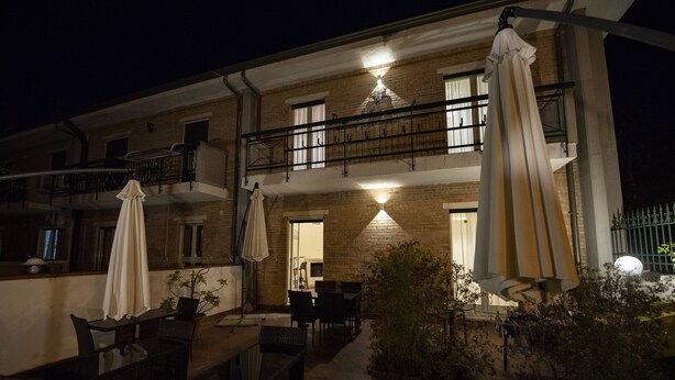 Un espace extérieur aménagé en terrasse, avec des tables et des chaises, un balcon et des plantes en pot.