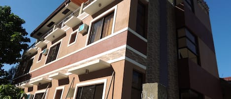 Um edifício de vários andares com varandas, janelas amplas e fachada em tijolo e estuque.