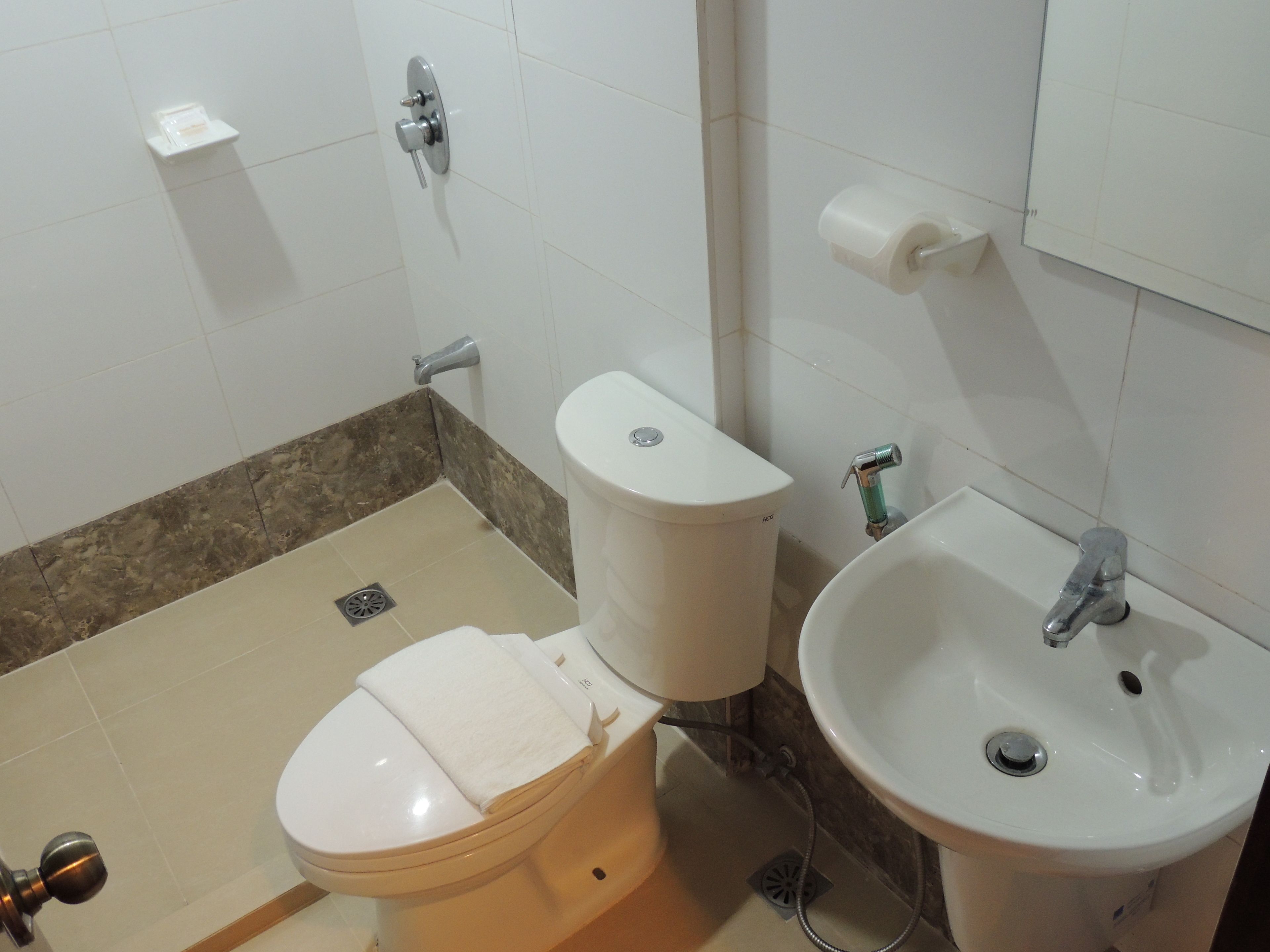 Un baño con inodoro, lavamanos y toallero.