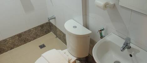 Un baño con inodoro, lavamanos y toallero.