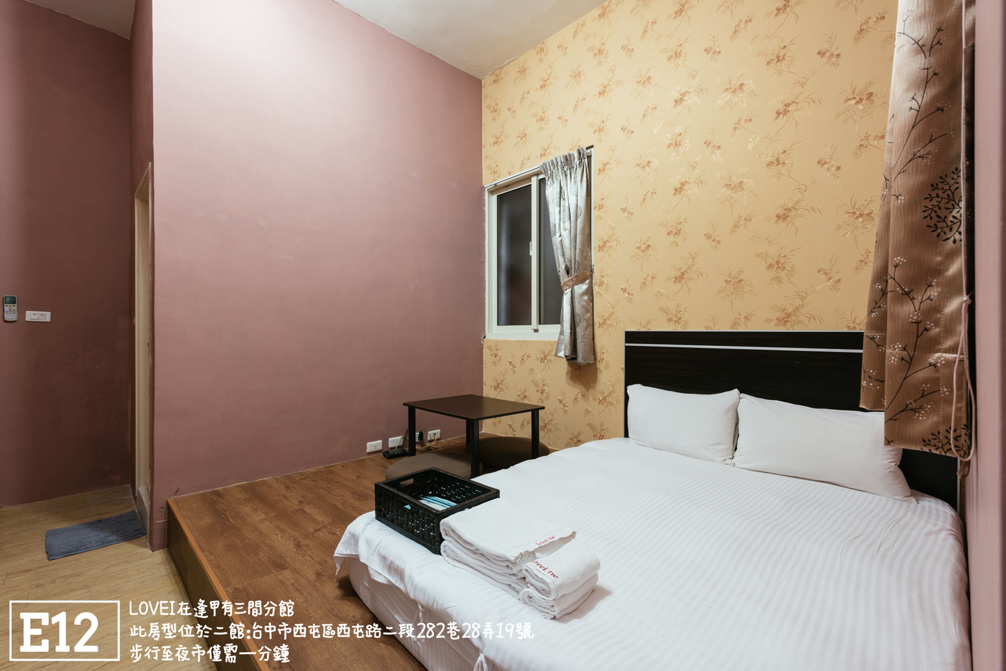 A hotel room with a bed, a small table, and a window with curtains.