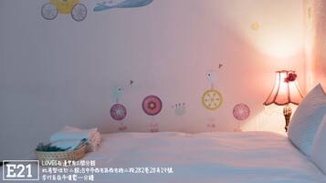 A bedroom with a bed, a nightstand, a lamp, and a wall decorated with children's drawings.