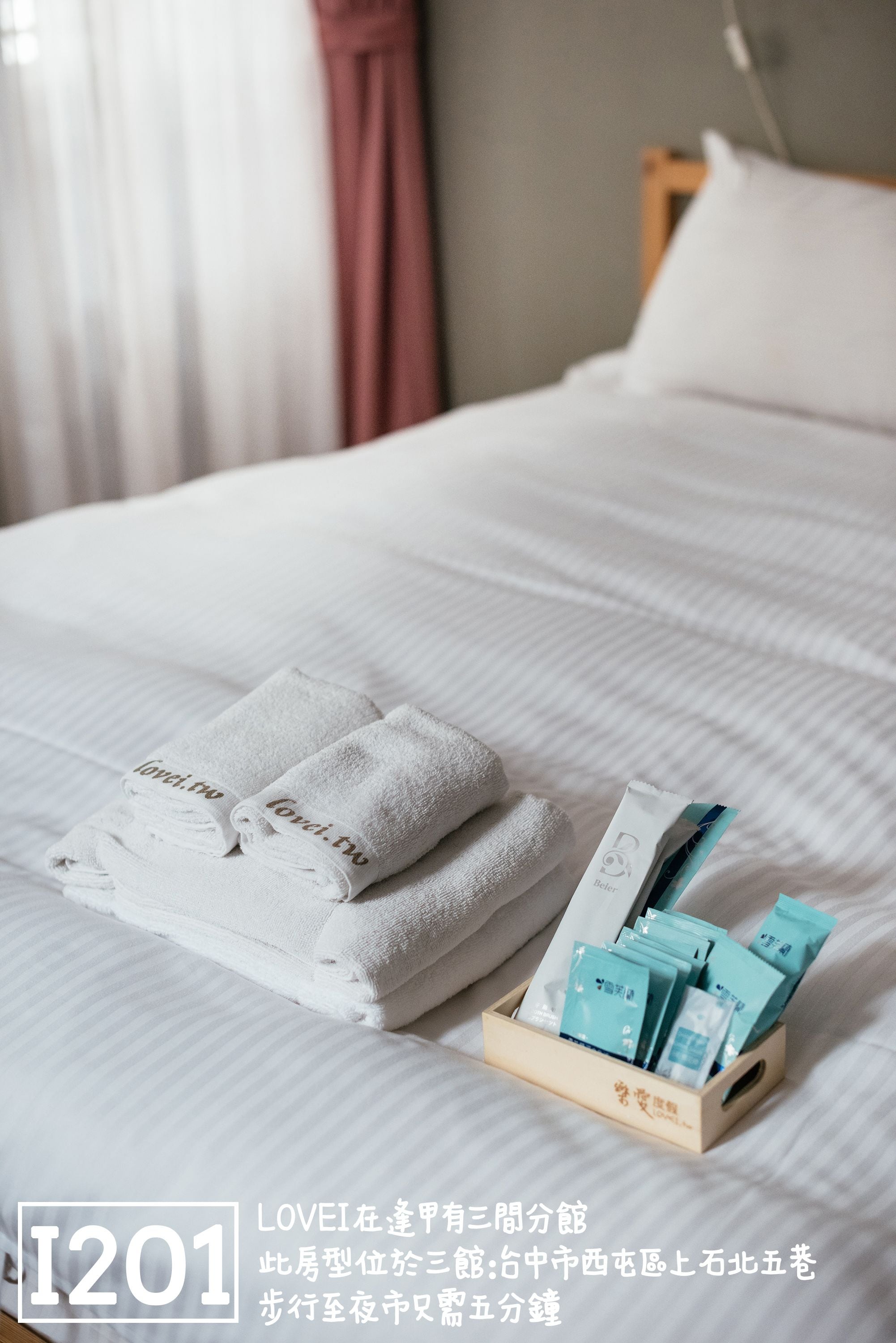A neatly made bed with folded white towels and a tray of toiletries.