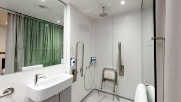 A modern bathroom with a white sink, a glass shower enclosure, and a towel rack.