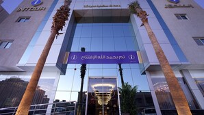 Un bâtiment moderne avec l’enseigne « INTOUR » et un texte en arabe au-dessus de l’entrée.