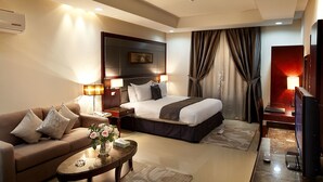 Une chambre d’hôtel avec un lit, un canapé, une télévision et un bureau avec une lampe.