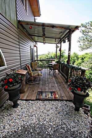 Une terrasse en bois avec des meubles d’extérieur, une pergola et des plantes en pot.