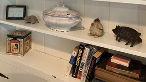 A shelf with decorative items, a sign spelling "Cottage," and books.