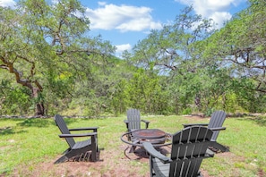 An outdoor seating area with Adirondack chairs and a circular fire pit.